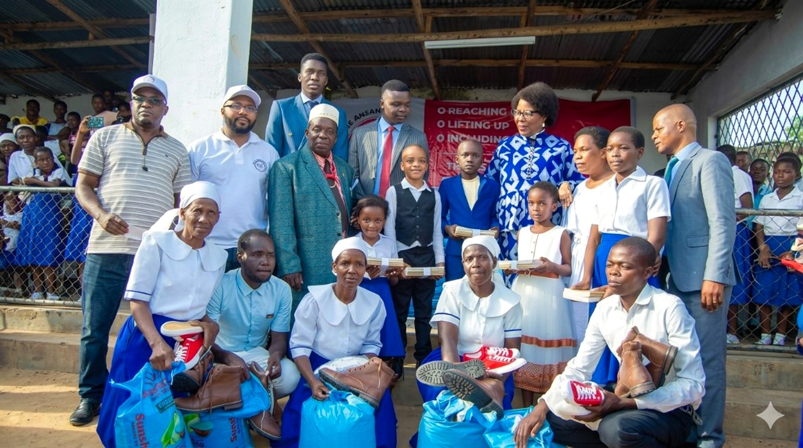 Dr. Jane Ansah Foundation community outreach with beneficiaries, donated supplies and the reaching out, lifting up and including banner